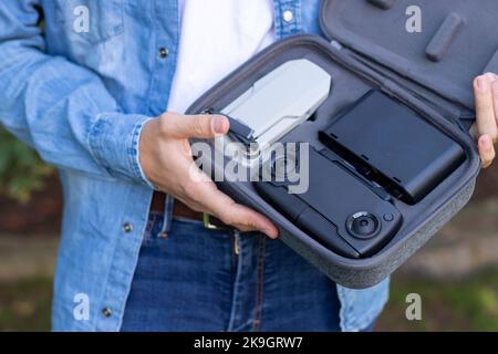 Close portrait of a small portable and foldable grey drone with 4k camera held in the hands of a young man Stock Photo