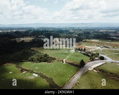 aerial view of meadow grass next to lush forest full of trees and road with no traffic in a quiet place, rotorua, new zealand Stock Photo