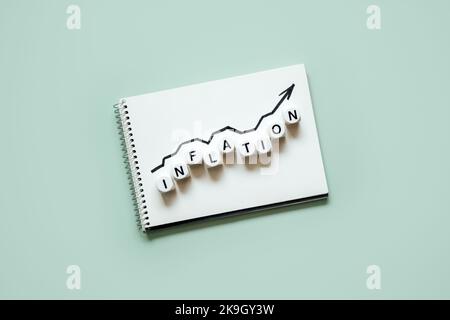 Inflation financial crisis concept. Growing up black arrow on open notepad and word Inflation on blue background. Rising cost of living. Stock Photo
