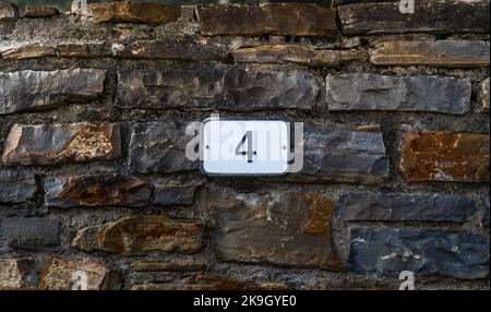 House number 4. Number 4 on a rock wall of a rural village street. Customizable house number sign. Stock Photo