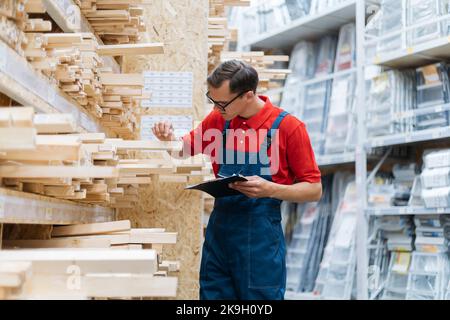 employee of a flooring store checking the markings on a laminated board. Stock Photo