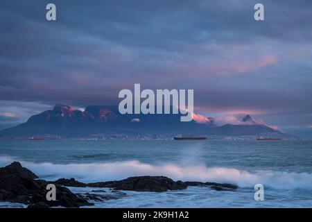 Iconic view across Table Bay of Table Mountain and Cape Town on a cloudy day at sunset from Bloubergstrand in the Western Cape. South Africa. Stock Photo