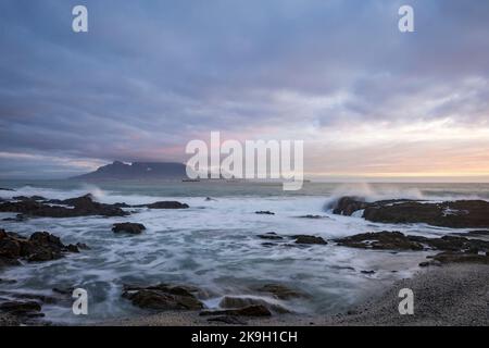 Iconic view across Table Bay of Table Mountain and Cape Town on a cloudy day at sunset from Bloubergstrand in the Western Cape. South Africa. Stock Photo