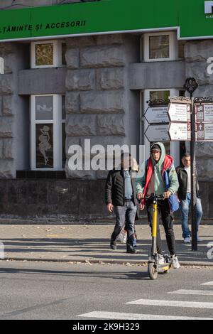 Chisinau, Moldova - October 15, 2022: A young guy crosses a pedestrian crossing on an electric scooter, selective focus. Stock Photo