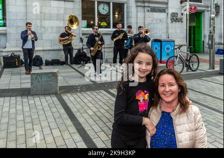 Cork, Ireland. 28th Oct, 2022. Today is the first day of the 44th Guinness Cork Jazz Festival. As well as bands playing in venues, the streets of Cork city host impromptu gigs. Enjoying 'Hyde Park Brass' from Leeds, UK were Laura Lynch and Miriam Nagle from Douglas. Credit: AG News/Alamy Live News Stock Photo