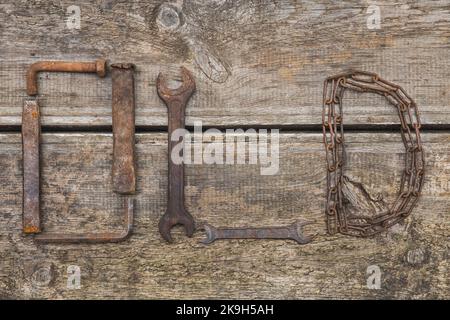 Word OLD made of rusty hand tools which lie on a rotten wooden table Stock Photo