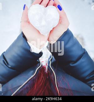 Top down view woman in two hands hold ice heart made of snow Stock Photo