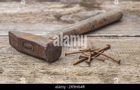 Old rusty hammer and nails on an unpainted wooden table Stock Photo