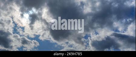 Sun shines through clouds on overcast sky - bright disc visible Stock Photo