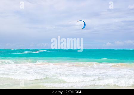 Kite surfer goes over shore waves under blue cloudy sky on a sunny day. Dominican republic. Bavaro beach Stock Photo