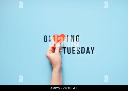 Giving Tuesday, Give, Help, Donation, Support, Volunteer concept with red heart in female hands and text Giving Tuesday on blue background. Its time Stock Photo