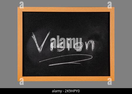 The word Vision handwritten with white chalk on blackboard with wooden frame, isolated on middle gray background Stock Photo