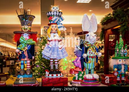 12-17-2021 Tulsa USA Alice in Wonderland Christmas figurines and nutcracker on display in Department store with blurred Christmas trees in background Stock Photo