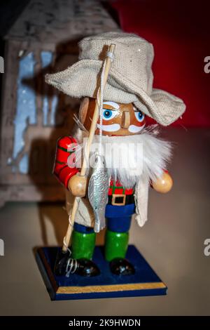 Fisherman nutcracker with fish on pole and linen hat with blurred background - close-up Stock Photo