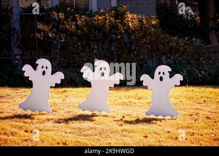 Halloween Decorations - Three cut-out ghosts dance in Autumn Yard Stock Photo