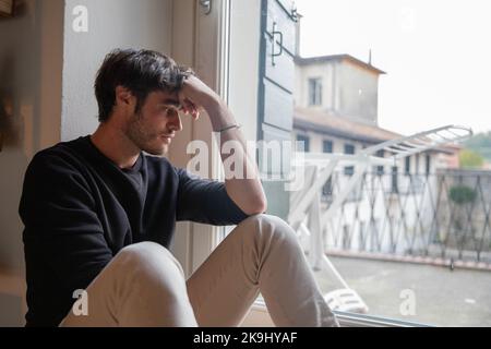 Lonely isolated young man sitting on the floor meditating. Depression concept. Stock Photo