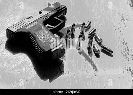 A Glock 19 pistol, manufactured in Austria, lies on a table along with several cartridges of 9mm ammunition. Stock Photo