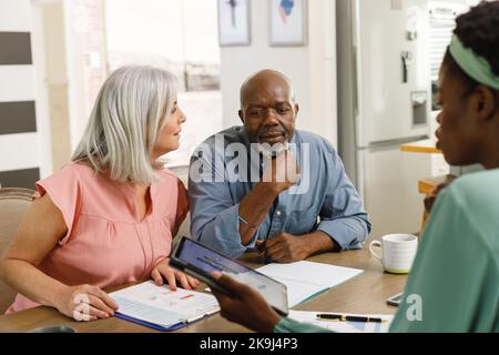 Senior diverse couple talking with african american female financial advisor Stock Photo