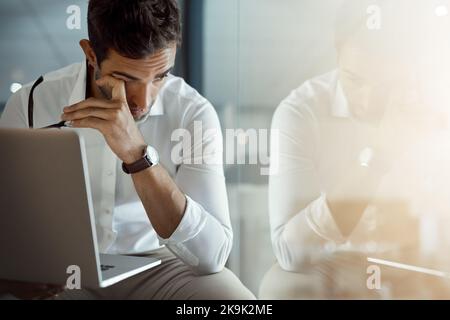 Feeling the strain. a young businessman looking stressed while working on his laptop in the office. Stock Photo