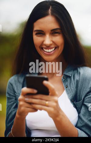 Nothing makes me happier than getting a heart emoji. Portrait of an attractive young woman using a mobile phone in a park. Stock Photo