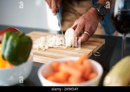 Good food requires onions. an unrecognizable man chopping onions on a cutting board. Stock Photo