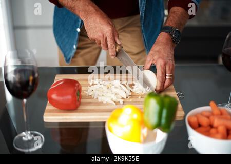 Starting dinner with the basics. an unrecognizable man chopping onions on a cutting board. Stock Photo