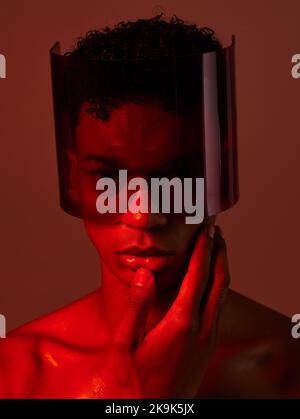Cyberpunk, glasses and man in red studio, lighting, model and fashion in the future. Dark, tech and face portrait of male with futuristic, edgy and Stock Photo