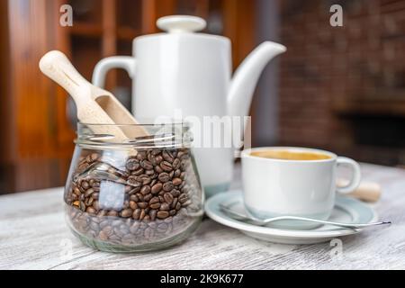 Coffee set with cup of freshly brewed coffee, porcelain coffee maker and glass jar with coffee beans. Stock Photo