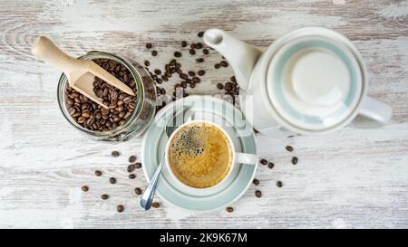 Coffee set with cup of freshly brewed coffee, porcelain coffee maker and glass jar with coffee beans. Stock Photo