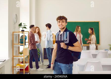 Portrait of smiling guy student with bag in audience looking at camera during break. Stock Photo