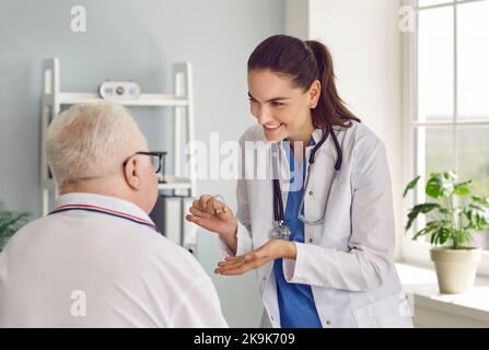 Doctor talks about benefits and prescribes hearing aid to elderly man who has become hard of hearing Stock Photo