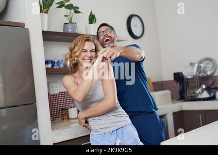 Happy hearts, happy home. a happy middle aged couple dancing in the kitchen at home. Stock Photo