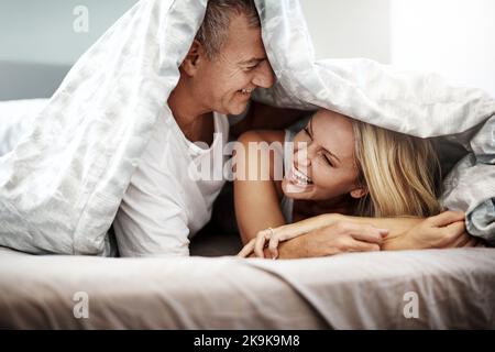 What happens under the covers, stays under the covers. an affectionate couple spending the day in bed. Stock Photo