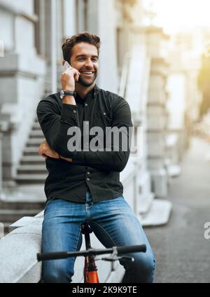 Im actually out for a cycle at the moment. a handsome young man making a phonecall while traveling through the city. Stock Photo