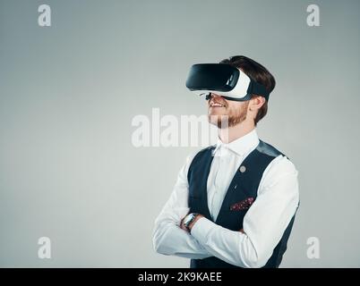 This is what modern business looks like. Studio shot of a handsome young businessman using a vr headset against a grey background. Stock Photo
