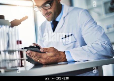 He only uses smart tools in his lab. a scientist using a digital tablet while working in a lab. Stock Photo