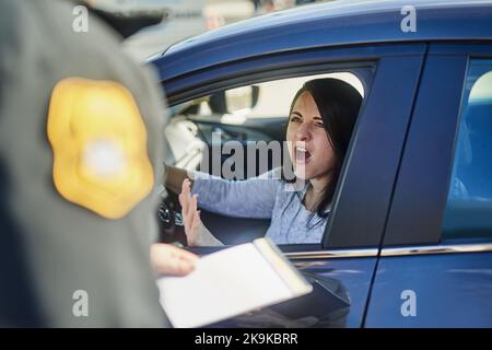 This is ridiculous. an unrecognizable male traffic officer issuing a ticket to a female civilian at a roadblock. Stock Photo