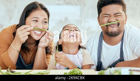 Happy asian family, play vegetables kitchen in portrait and smile together at table for bonding time. Mom dad, child happiness in comic home and Stock Photo