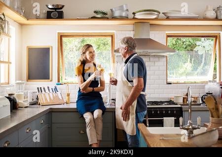 Love, wine and mature couple in kitchen cooking, drinking and spending free time together in home. Retirement, happy man and woman with wine glass Stock Photo