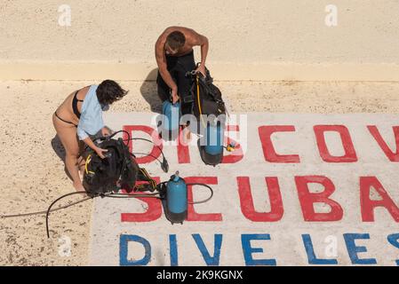 Agios Nikolaos, Crete, Greece. 2022. Couple at dive school preparing equipment to go diving. Stock Photo