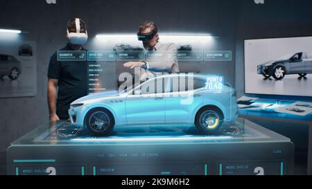 Two development engineers in the studio are designing an eco-friendly sustainable standard electric vehicle using 3D modeling technology and VR headsset. 3D interface of diagnostic application. Stock Photo