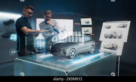 Two development engineers in the studio are designing an eco-friendly sustainable standard electric vehicle using 3D modeling technology and VR headsset. 3D interface of diagnostic application. Stock Photo