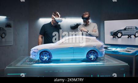 Two development engineers in the studio are designing an eco-friendly sustainable standard electric vehicle using 3D modeling technology and VR headsset. 3D interface of diagnostic application. Stock Photo