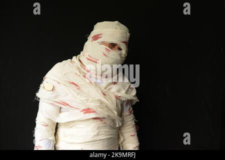 Bandaged mummy in standing position with black background on Halloween day. Stock Photo