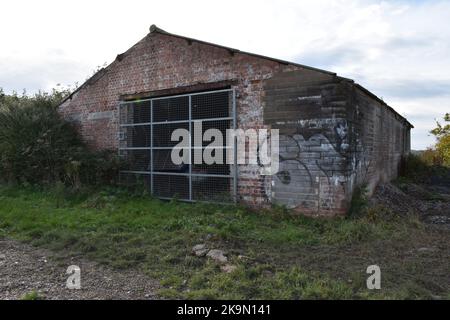 Derelict Red Brick Farm Building With Graffiti, Urban Comes To The Country Below Gallows Down Nr Inkpen West Berks. Old Rave Site. Stock Photo