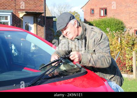 Man fitting a new windscreen wiper blade to his car. replacing the worn blade to clean his windows. Stock Photo