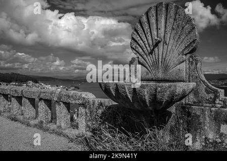 Fountain by the sea for pilgrims on the Camino de Santiago in the sunshine of a beautiful morning with spring clouds Stock Photo