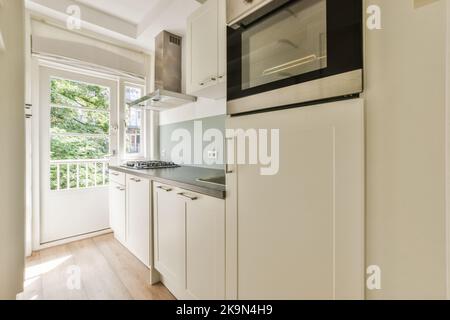 Contemporary cupboard located under stylish exhaust hood in spacious light kitchen at home Stock Photo