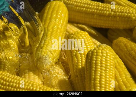 Process of cooking fresh mature corn. Sale of freshly boiled hot corn at fair. Natural yellow background. Close-up. Selective focus. Stock Photo