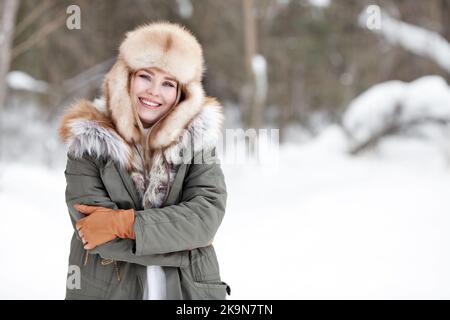 Frozen woman in leather coat with fur hood standing outdoors with her  gloved hand covering her face. Girl trying to keep warm, concept of cold  weather Stock Photo - Alamy